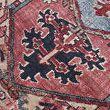 Close up of the Neyland Area Rug, featuring a traditional design in red, navy, beige, and blue. Texture