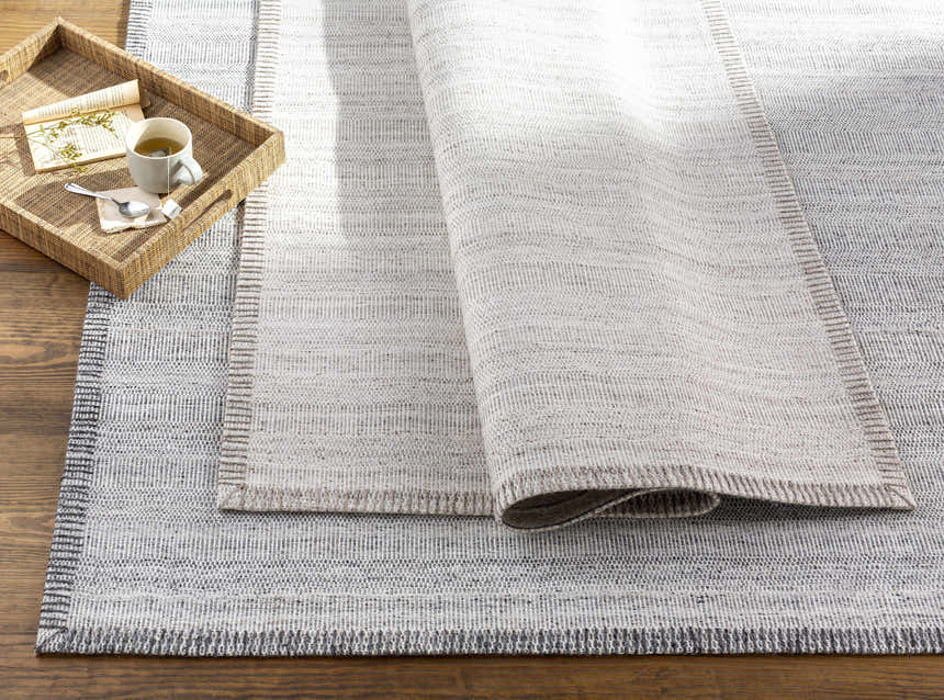 Close-up of the hand woven Denison Viscose Area Carpet. Cream, gray, and oatmeal colors with a subtle striped pattern. Styleshot