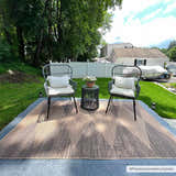 Outdoor patio scene with camel and dark brown Ijlal Washable Area Rug, two chairs, and a small table with flowers. Roomscene-Rectangle