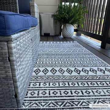 Outdoor patio scene with a black and white Imboden rug, wicker furniture, and potted fern. Roomscene-Rectangle