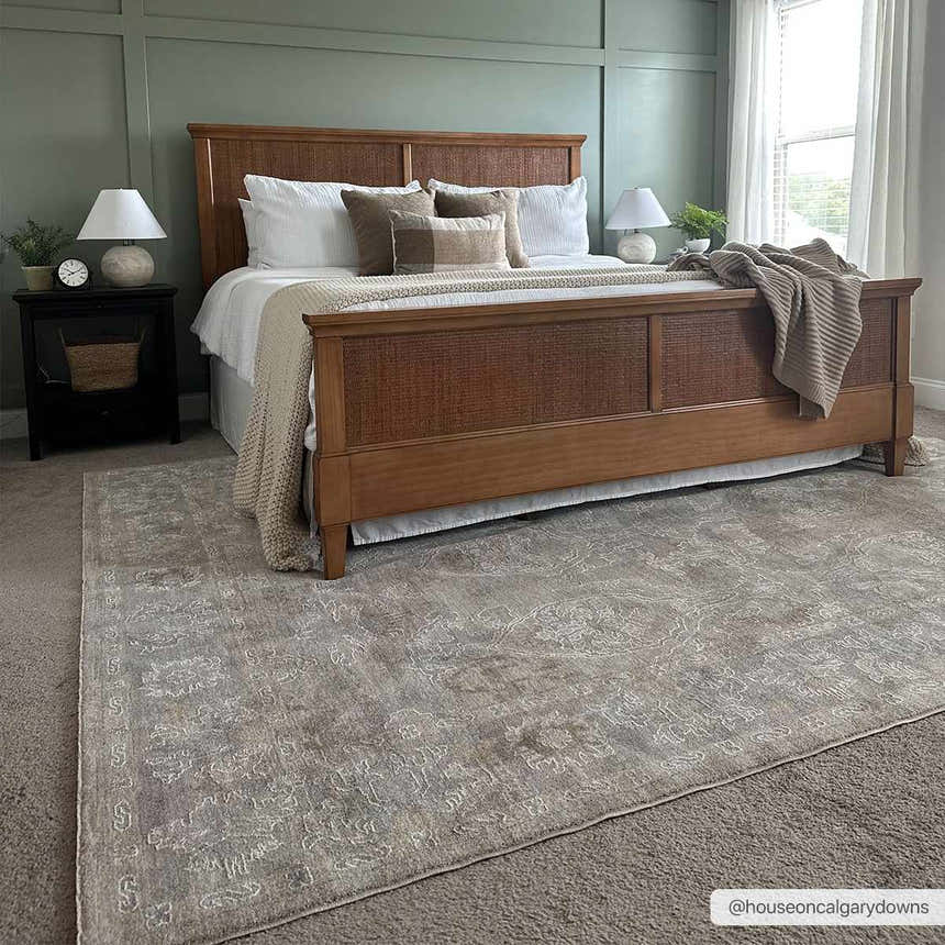 Bedroom scene with a cloud gray Istas Thick Luxe Area Rug under a wood bed, creating a farmhouse style. Roomscene-Rectangle