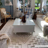 Living room scene with Ivory Alya 3D Medallion Fringe Area Rug, white sofa, blue plaid chair, and white coffee table. Roomscene-Rectangle