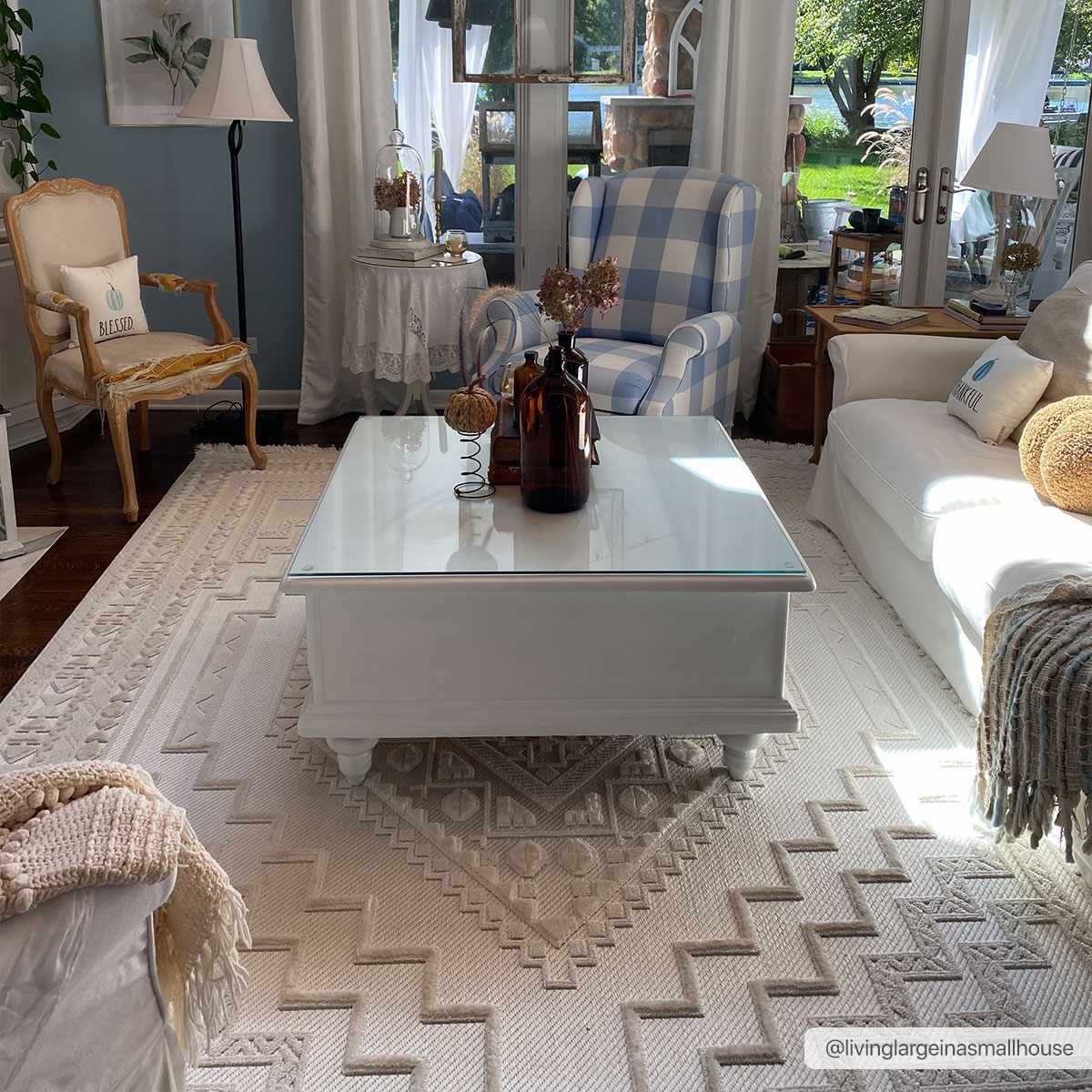 Living room scene with Ivory Alya 3D Medallion Fringe Area Rug, white sofa, blue plaid chair, and white coffee table. Roomscene-Rectangle
