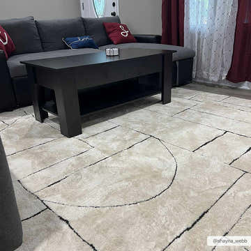 Living room scene with a Keats Black & White rug, gray sofa, black coffee table, and burgundy accents. Roomscene-Rectangle