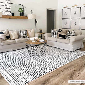 Living room scene with Keita Cream & Black Grid Plush Rug, beige sofas, wood floors, and black and white decor. Roomscene-Rectangle