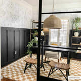 Home office with black walls and Kieu Mustard & Ivory Checkered Area Rug, woven stools, and a black desk. Roomscene-Rectangle