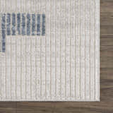 Close-up of Brisa Area Rug's gray and blue abstract pattern and textured weave on a dark wood floor. Swatch
