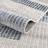 Close-up of the Brisa Area Rug showing its blue and gray abstract pattern and soft, textured pile. Fold