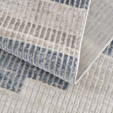 Close up of Brisa Area Rug showing blue and gray abstract pattern and woven texture. Fold