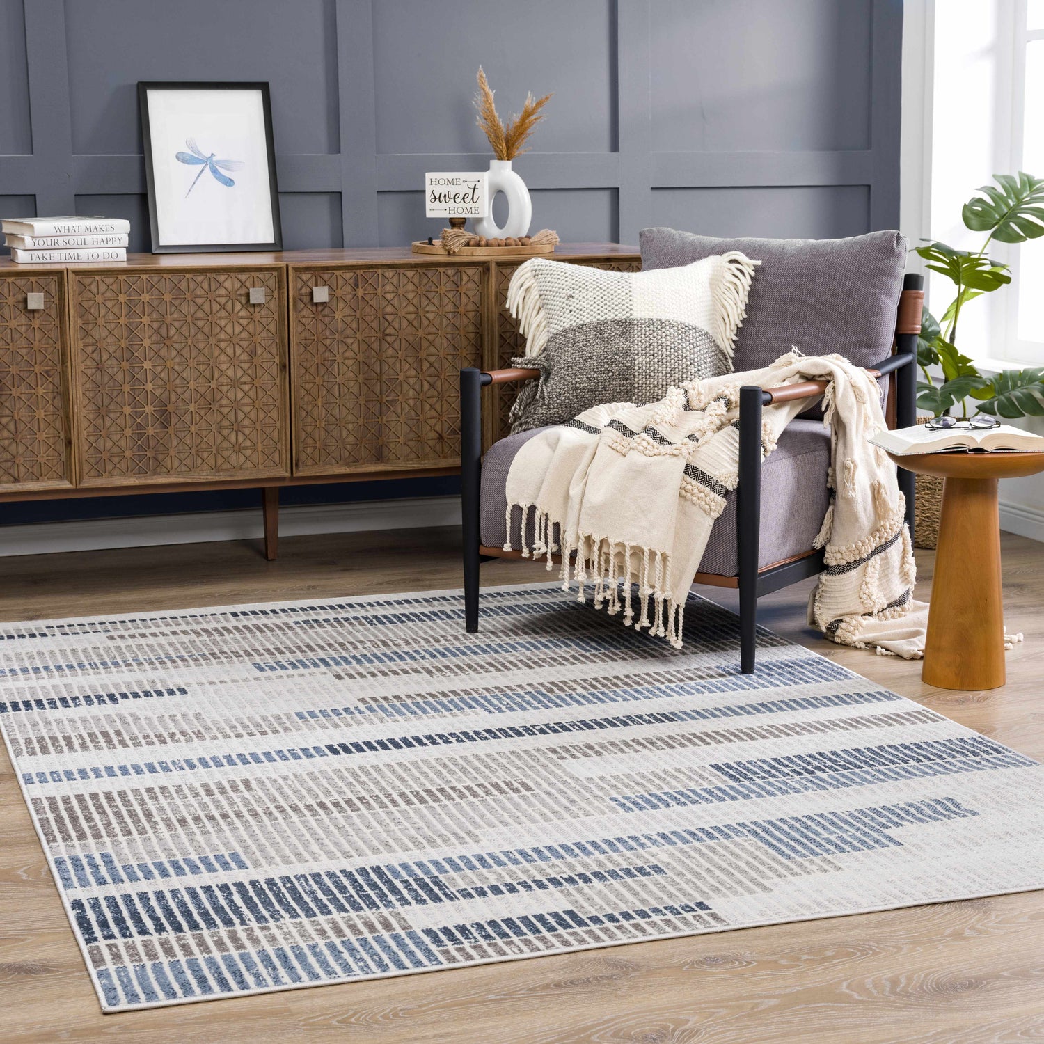 Living room scene with Brisa Area Rug in blue and gray, styled with a wood cabinet and gray armchair. Roomscene-Rectangle