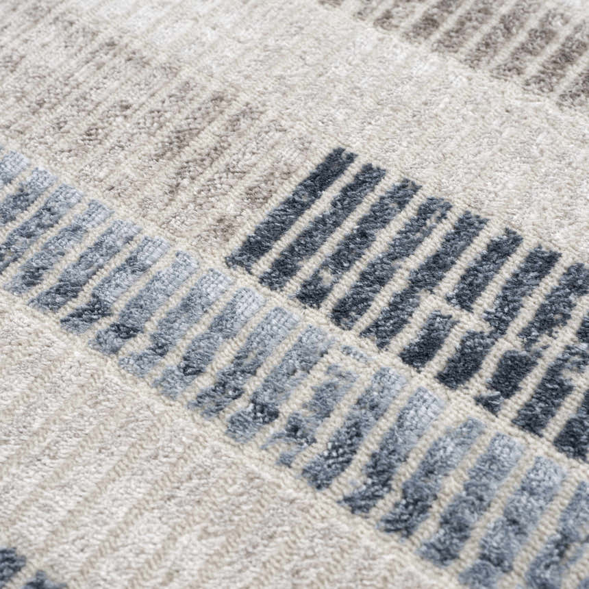 Close up of the Brisa Area Rug showing a textured, modern abstract design in blue, gray, and ivory. Texture