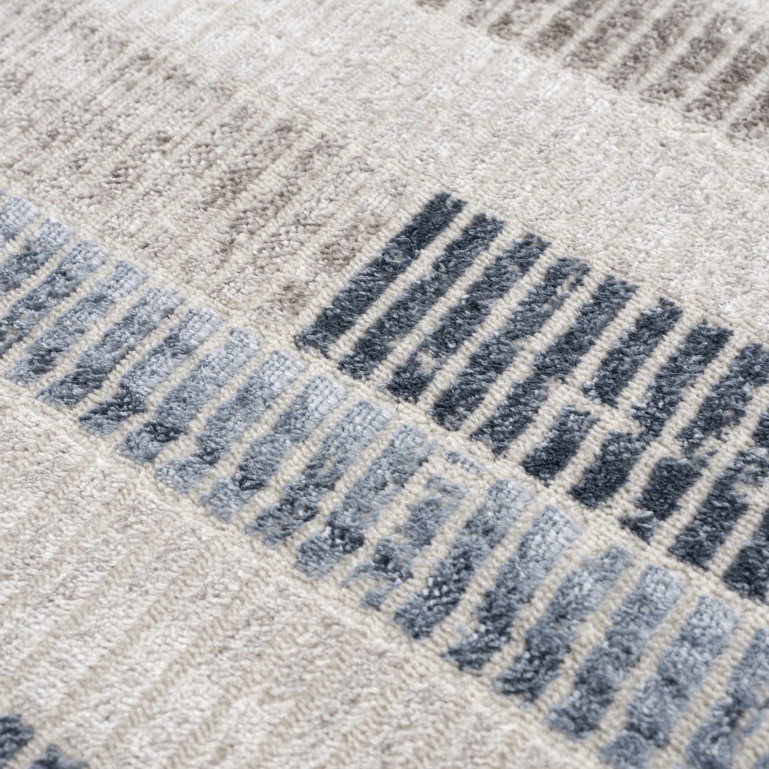 Close up of the Brisa Area Rug showing a textured, modern abstract design in blue, gray, and ivory. Texture