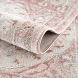Close-up of the Zora Pink Area Rug showing its traditional vintage pattern, soft texture, and gray and pink colors. Fold