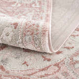 Close-up of the Zora Pink Area Rug showing its traditional vintage design, soft texture, and gray and pink colors. Fold