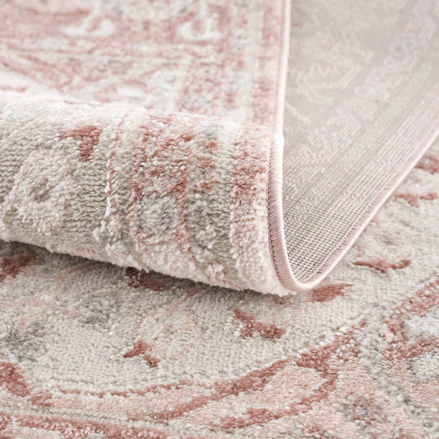 Close-up of the Zora Pink Area Rug showing its traditional vintage design, soft texture, and gray and pink colors. Fold