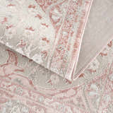 Close-up of the Zora Pink Area Rug showing its traditional vintage pattern, soft pink, and gray colors. Fold