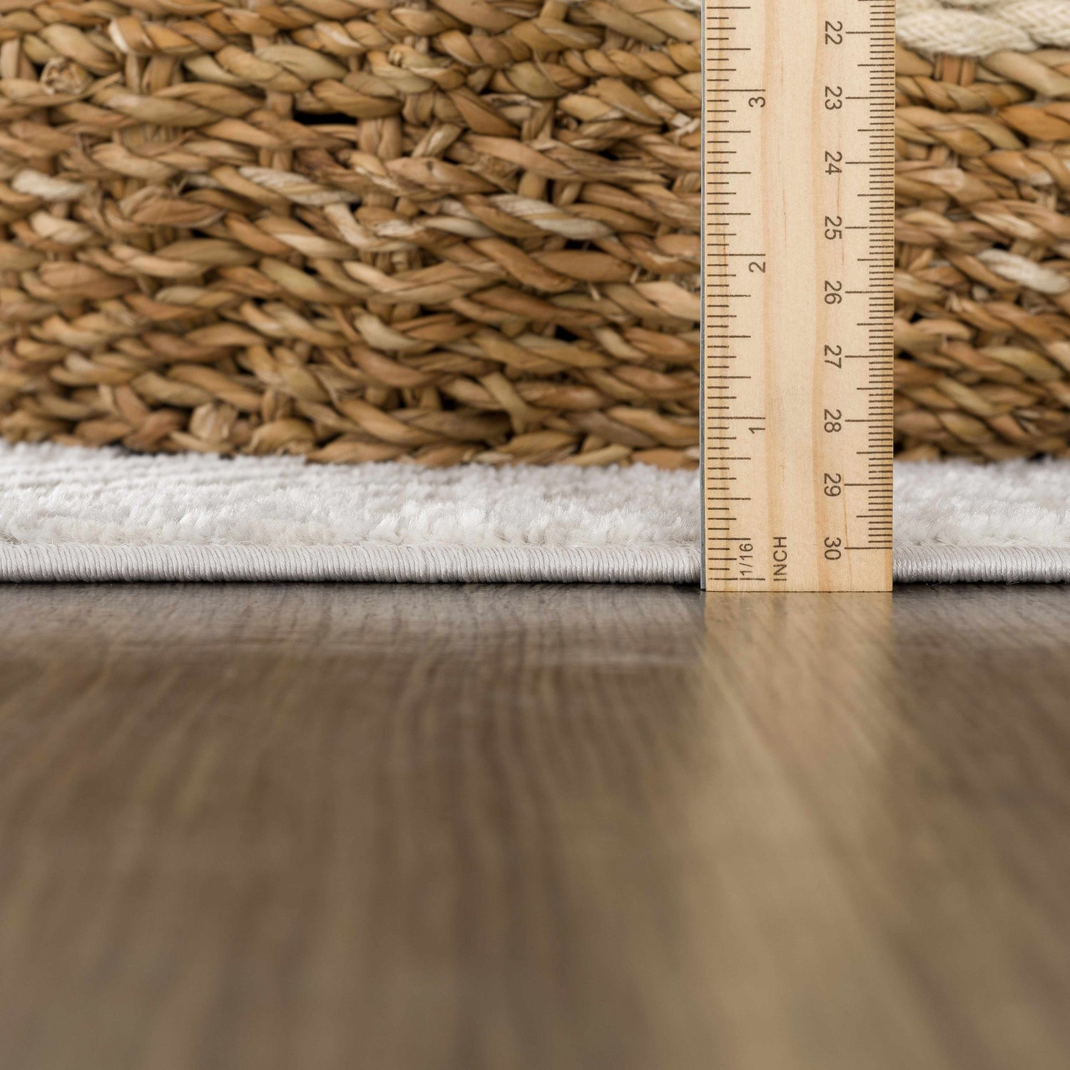 Close-up of the Bucky Area Rug showing the pile height with a ruler, next to a woven basket. Pile