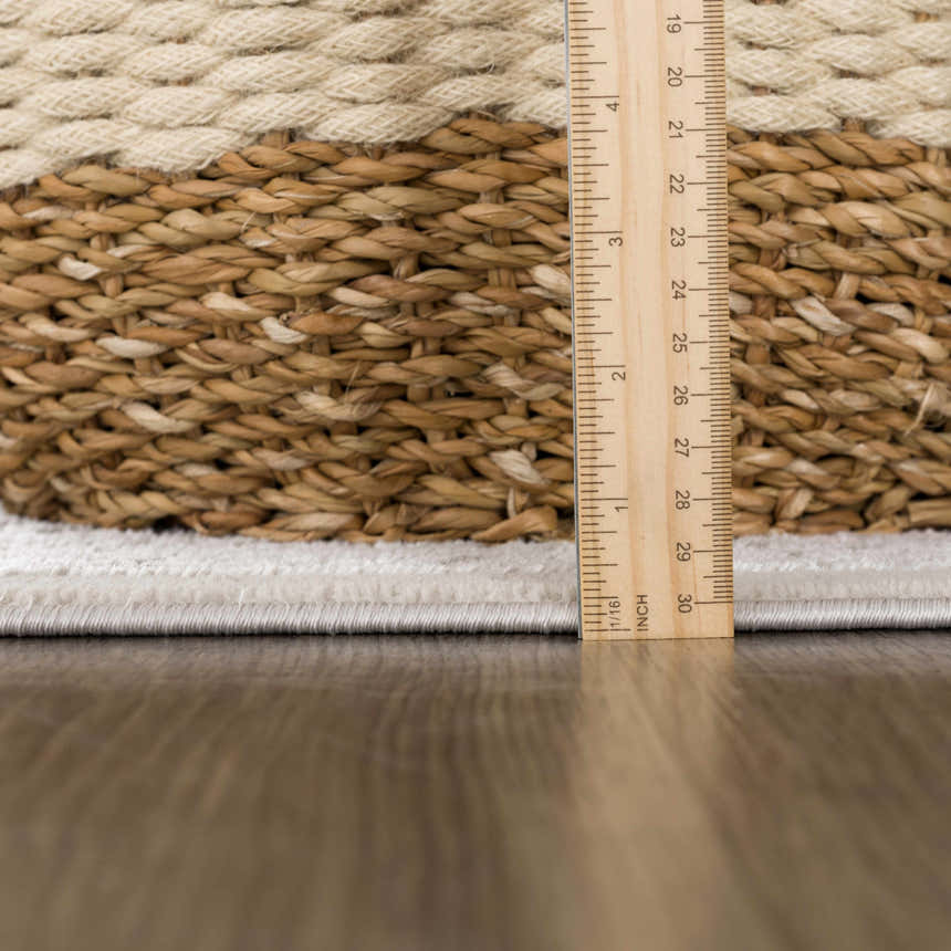 Close-up of the Damla Area Rug showing the gray and beige braided texture and pile height with a ruler. Pile