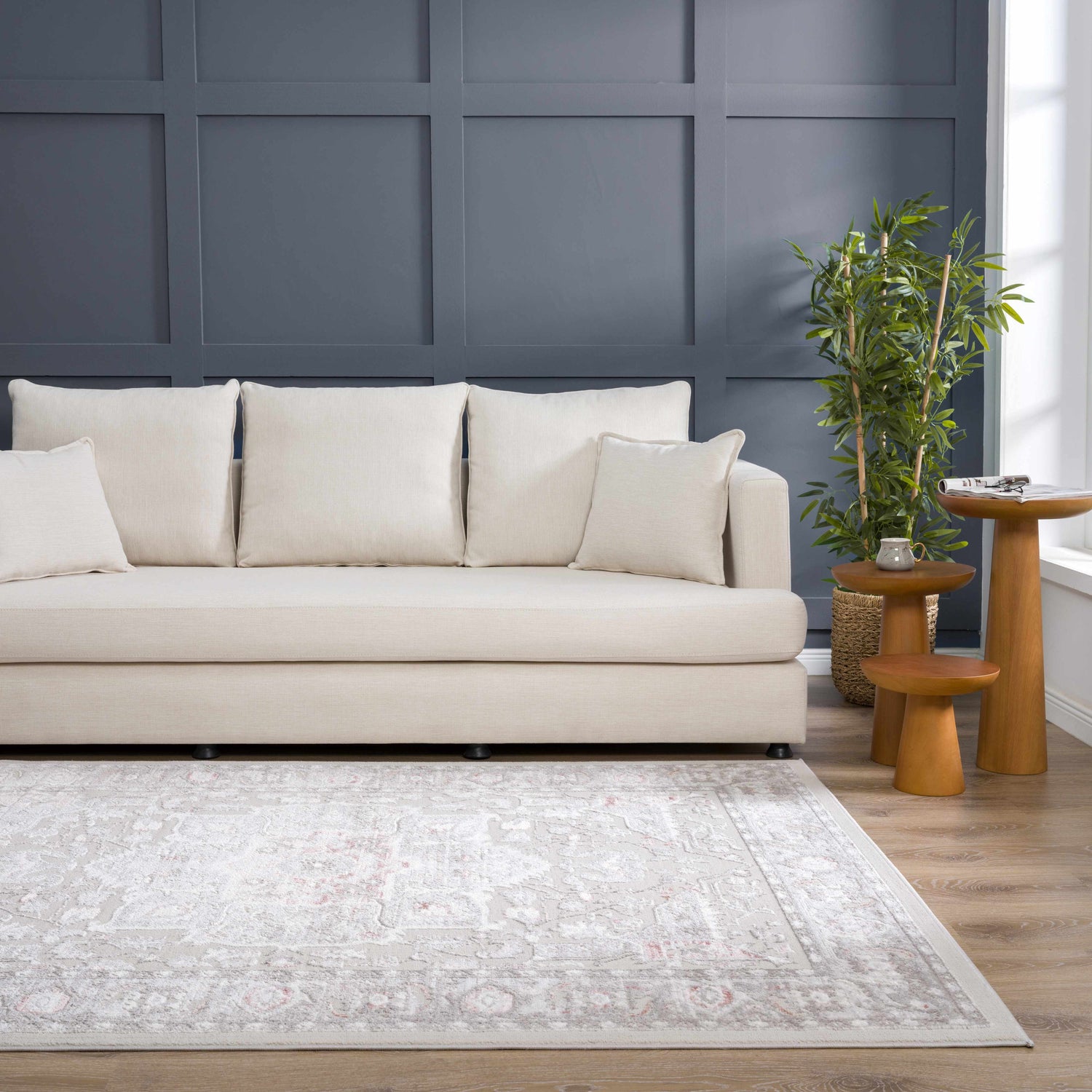 Living room with a gray Damla Area Rug, cream sofa, wood side tables, and a dark blue accent wall. Roomscene-Rectangle