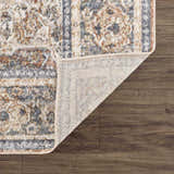 Close-up of the Arias Blue Boutique Washable Rug showing its traditional pattern, faded driftwood, nutmeg, and gray colors. Fold