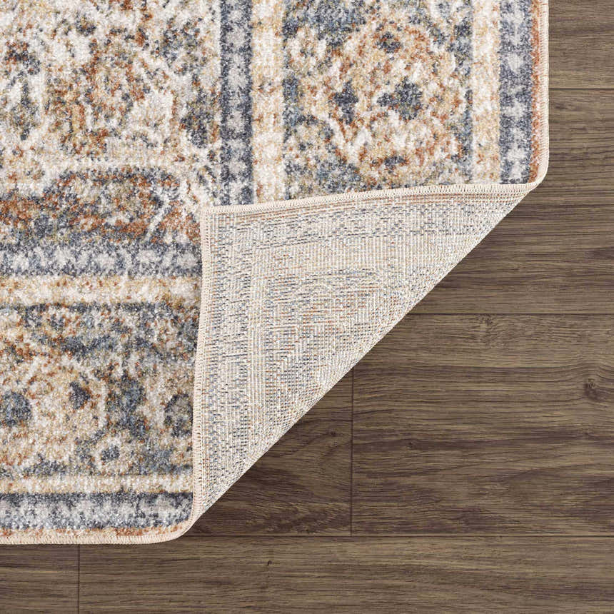 Close-up of the Arias Blue Boutique Washable Rug showing its traditional pattern, faded driftwood, nutmeg, and gray colors. Fold