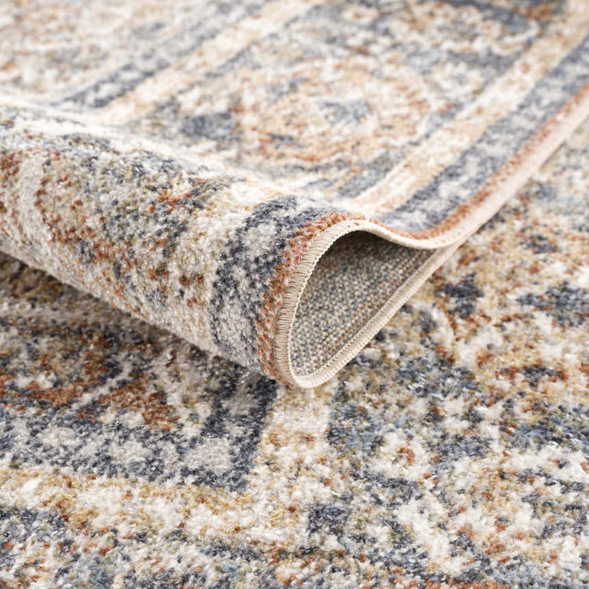 Close-up of the Arias Blue Boutique Washable Rug showing the traditional pattern, soft texture, and blended beachhouse colors. Fold