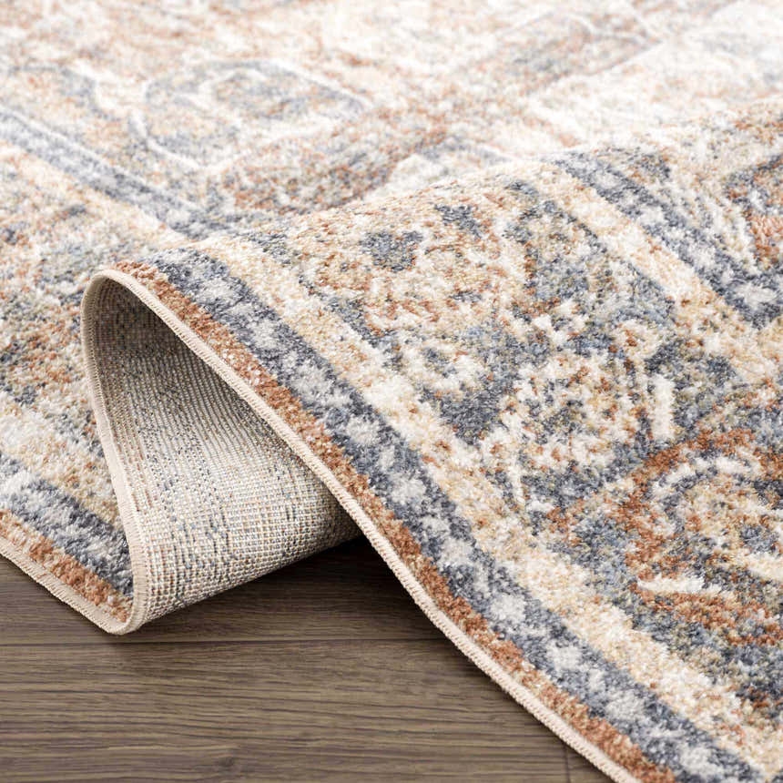 Close-up of the Arias Blue Boutique Washable Rug showing its faded driftwood, nutmeg, and gray traditional pattern. Fold