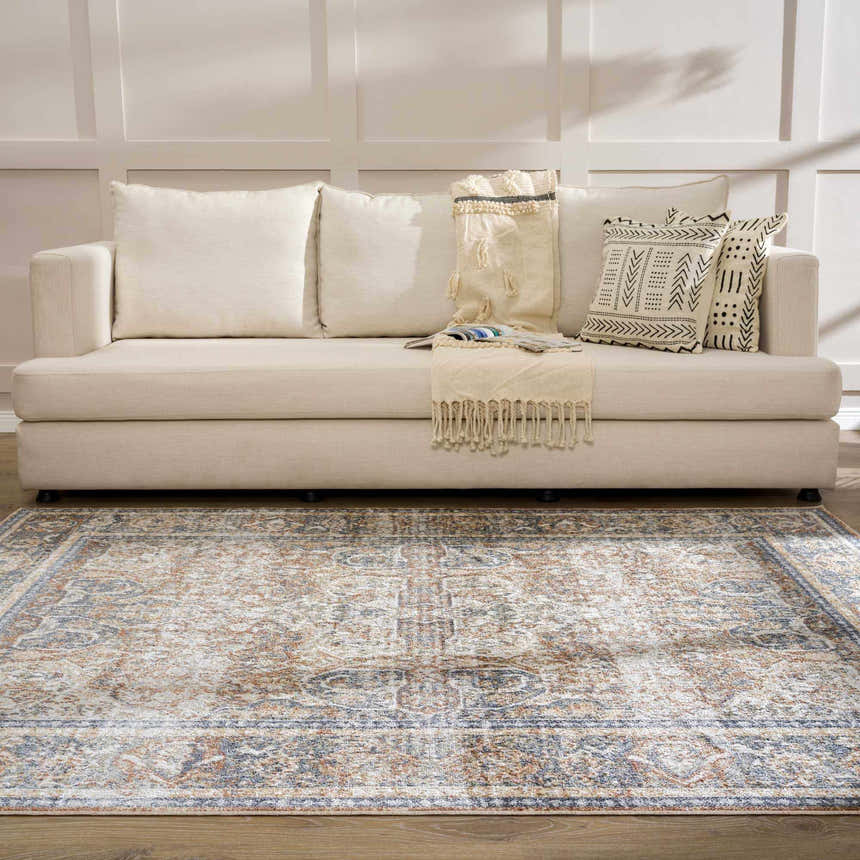 Living room scene with a beige sofa and the Arias Blue Boutique Washable Rug, showcasing its faded driftwood, clay, and blue oriental pattern. Roomscene-Rectangle