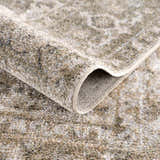 Close-up of the Gael Boutique Washable Rug showing its tan, olive, and light blue vintage pattern and soft, textured weave. Fold