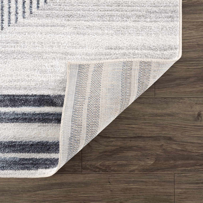 Close up of the Thad Medium Gray Washable Area Rug showing geometric design, soft texture, and durable backing. Fold