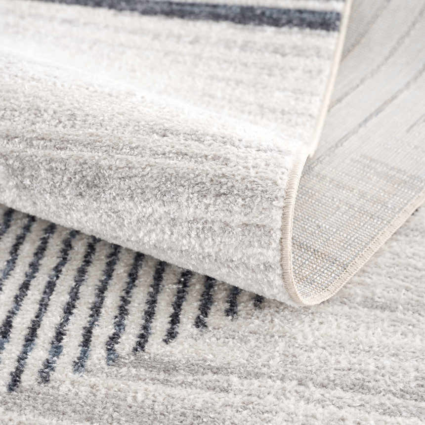 Close-up of the Thad Medium Gray Washable Area Rug showing its geometric stripe pattern and soft, textured pile. Fold