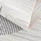 Close-up of the Thad Medium Gray Washable Area Rug showing its geometric pattern, soft texture, and durable backing. Fold