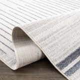 Close-up of the Thad Medium Gray Washable Area Rug, showing its bone and gray linear geometric pattern and soft, textured pile. Fold