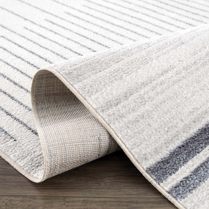 Close-up of the Thad Medium Gray Washable Area Rug, showing its bone and gray linear geometric pattern and soft, textured pile. Fold