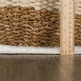 Close-up of the bone-colored, plush pile and braided edge of the Thad Medium Gray Washable Area Rug, with a ruler. Pile