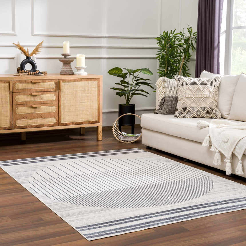 Living room scene with a Thad Medium Gray Washable Area Rug, bone sofa, wood cabinet, and plants for a modern, cozy feel. Roomscene-Rectangle
