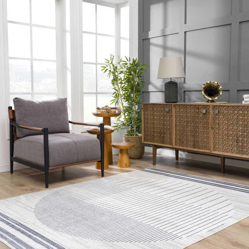 Living room scene with a gray chair and the Thad Medium Gray Washable Area Rug featuring a geometric design. Roomscene-Rectangle