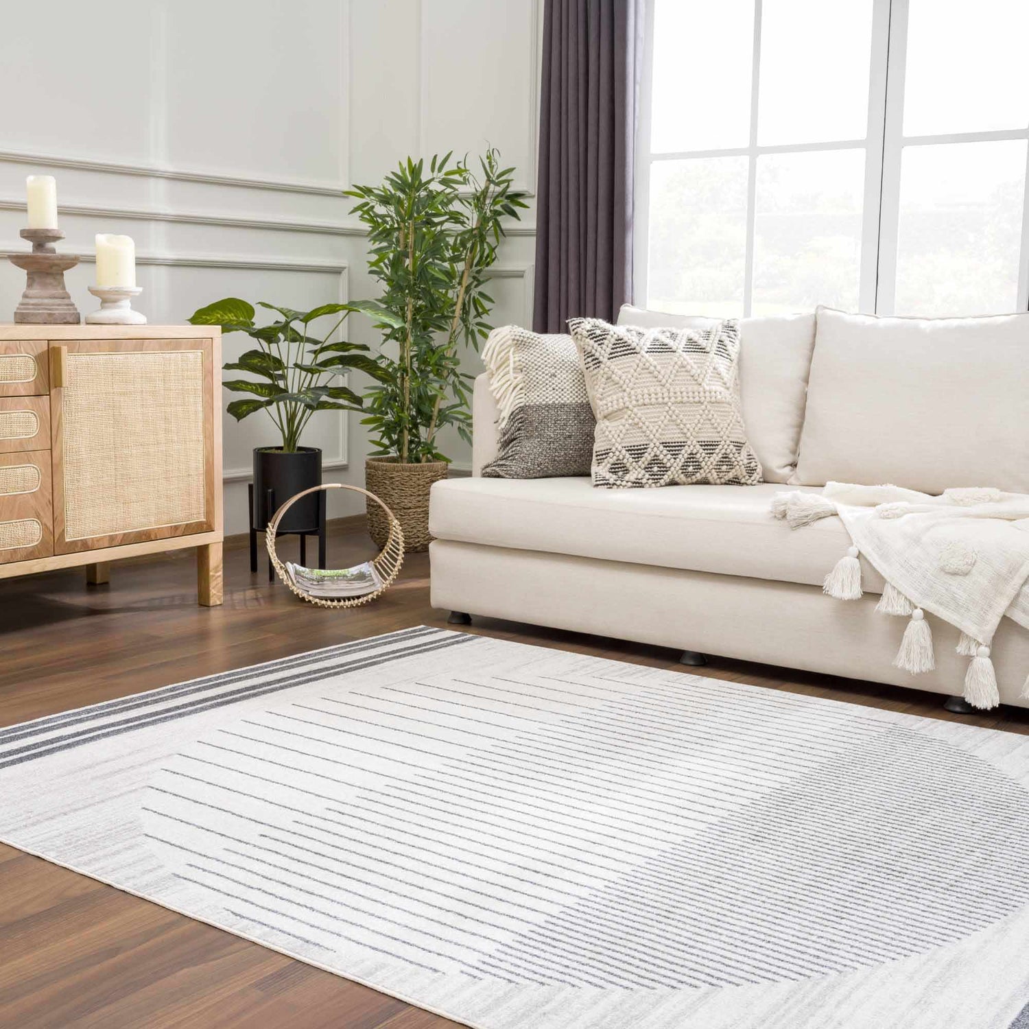 Living room scene with a Thad Medium Gray Washable Area Rug, bone sofa, wood cabinet, and plants for a contemporary style. Roomscene-Rectangle