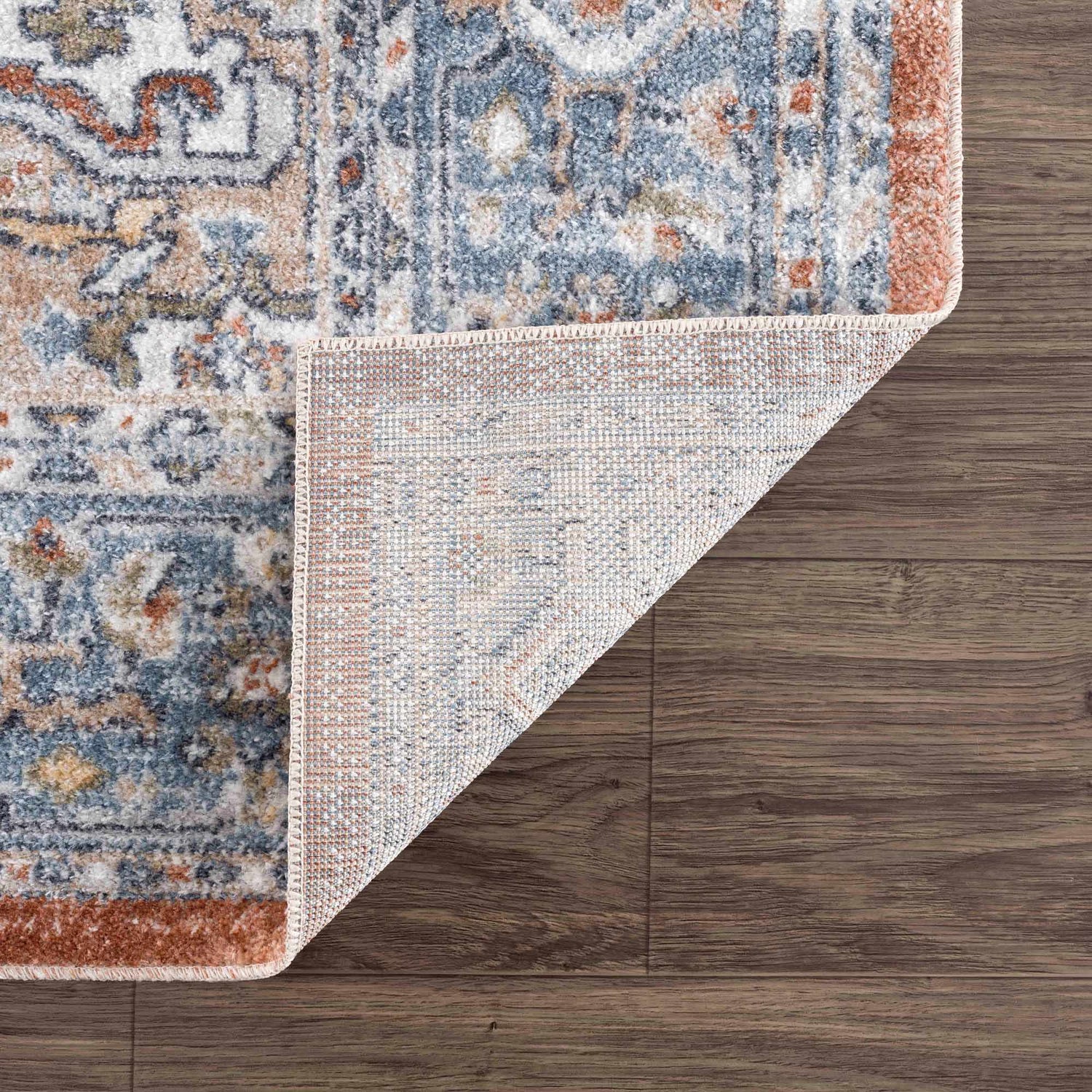 Close-up of the Ember Washable Area Rug in Beachhouse color showing traditional pattern and durable machine woven construction. Fold