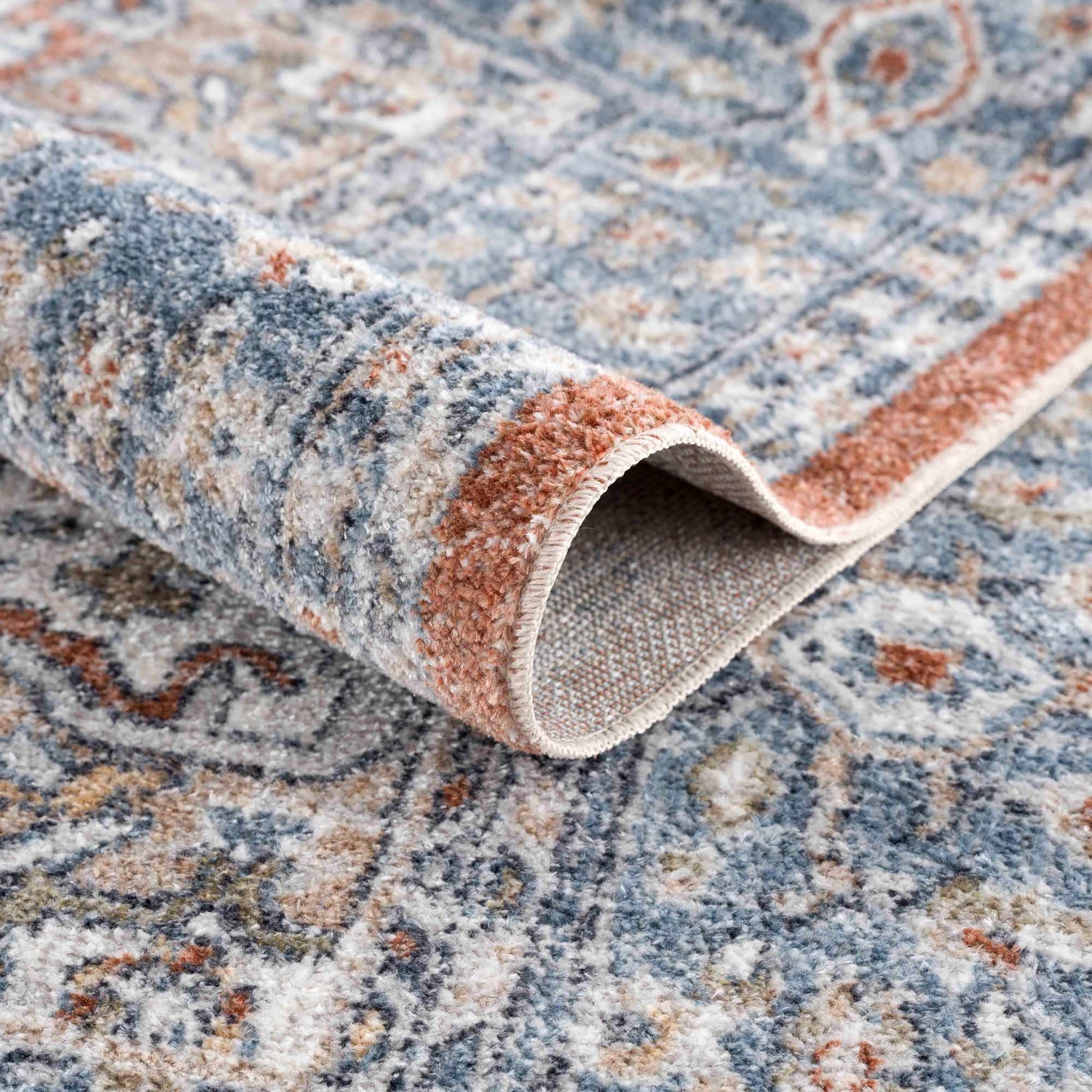 Close-up of the Ember Washable Area Rug in Beachhouse, showing its traditional pattern and soft, textured weave. Fold