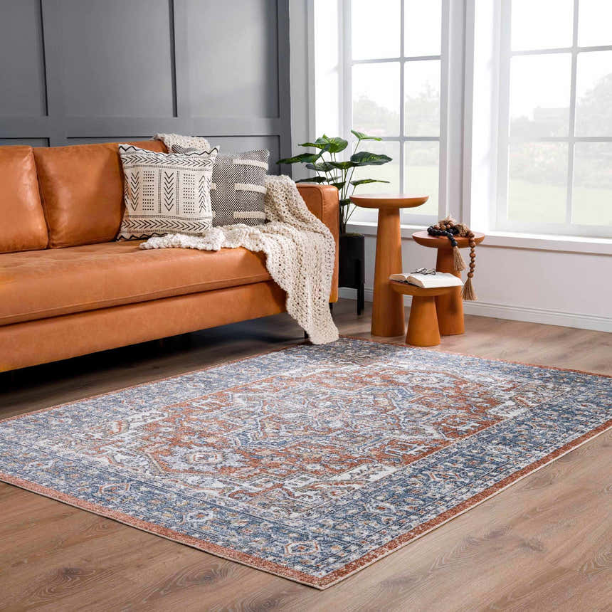 Living room scene with leather sofa and Ember Washable Area Rug in beachhouse, charcoal, clay, copper, and faded driftwood colors. Roomscene-Rectangle