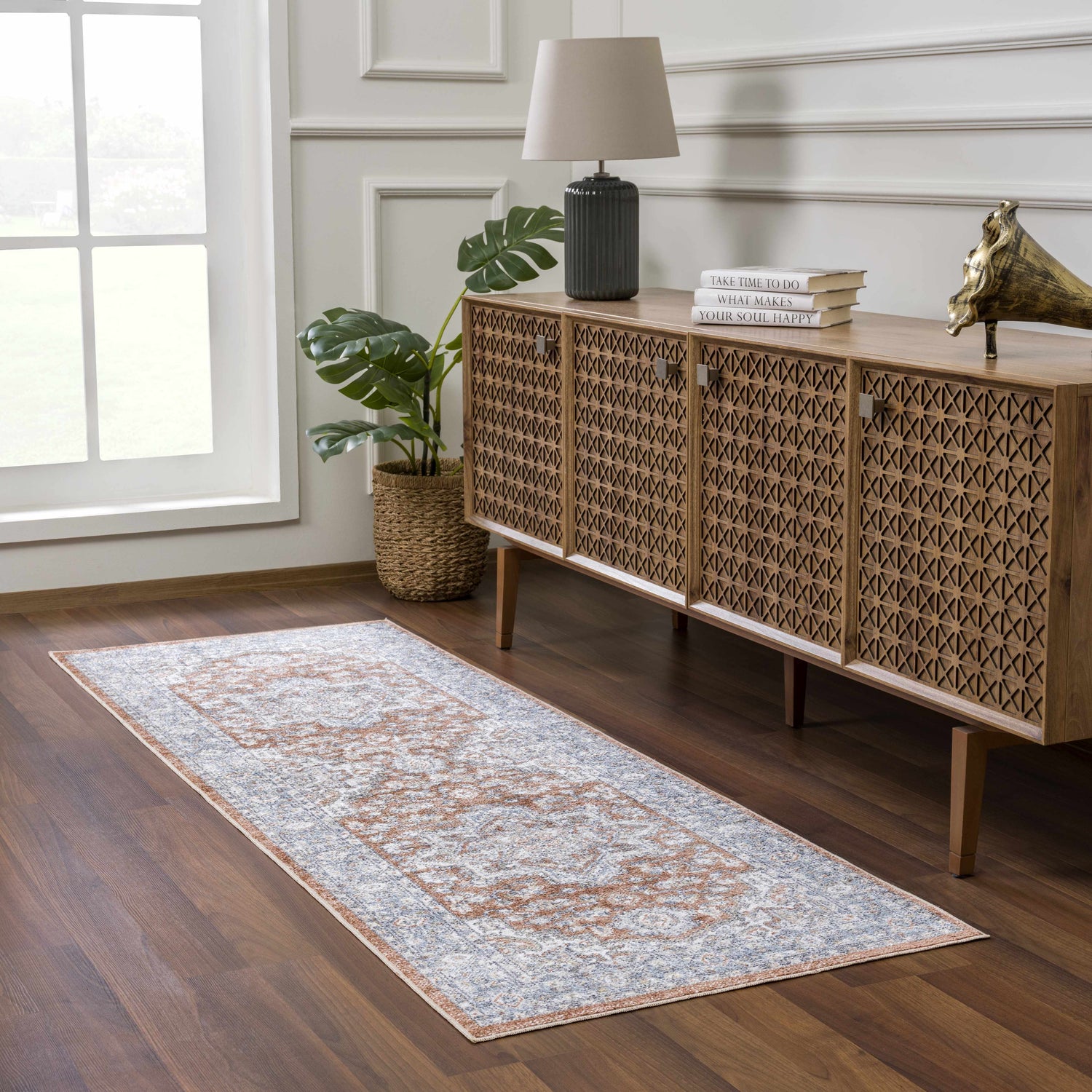 Entryway with Ember Washable Area Rug in Faded Driftwood, wood floors, and console table with books and lamp. Roomscene-Runner