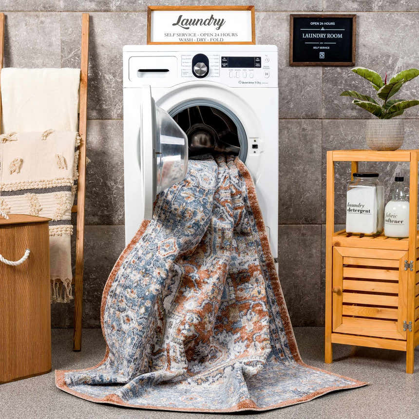 Styled laundry room scene with the Ember Washable Area Rug in Beachhouse color coming out of the washing machine. Washing-Machine