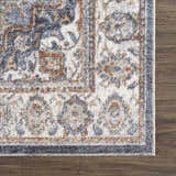 Close-up of Aurum Blue & Beige Washable Area Rug showing traditional floral pattern, blue, beige, and rust colors, and soft texture. Swatch