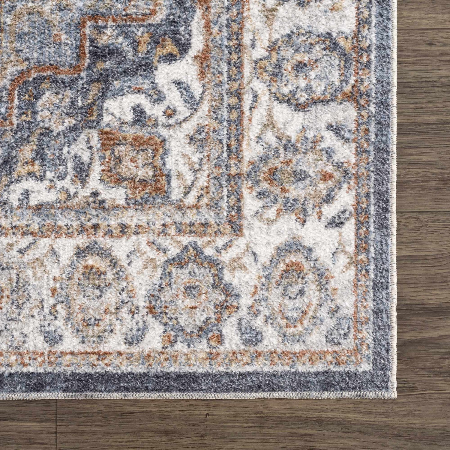 Close-up of Aurum Blue & Beige Washable Area Rug showing traditional floral pattern, blue, beige, and rust colors, and soft texture. Swatch