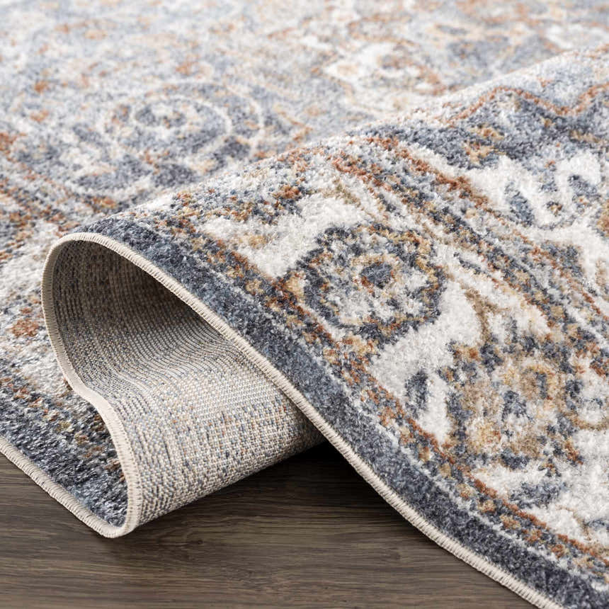 Close-up of Aurum Blue & Beige Washable Area Rug showing traditional floral pattern and texture in gray, rust, and off-white. Fold