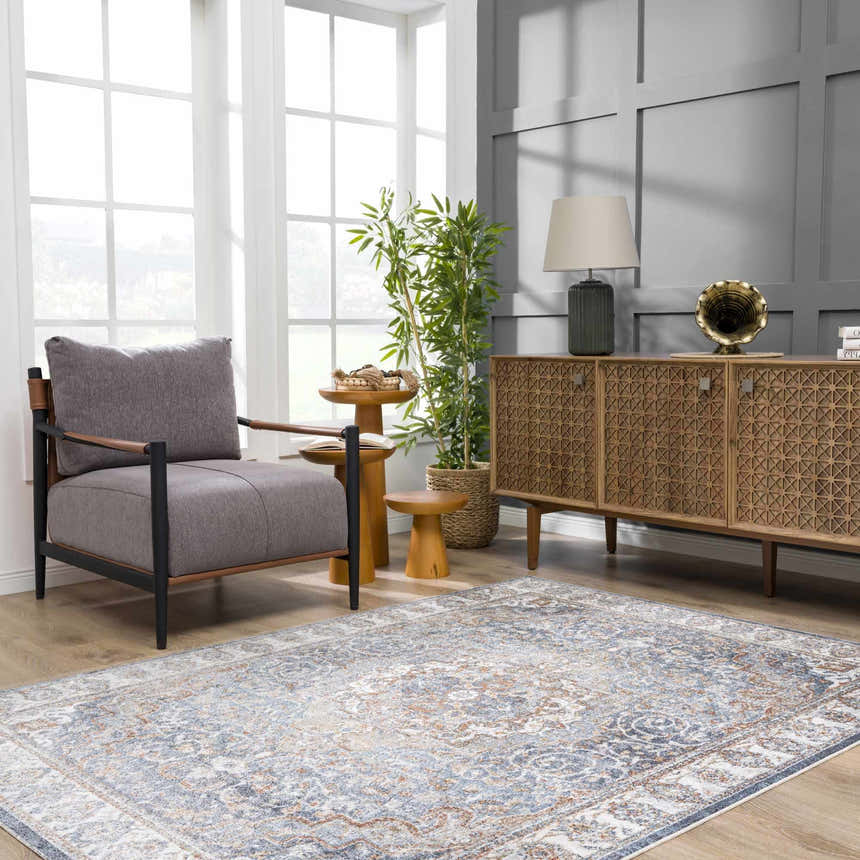 Living room scene with gray chair and Aurum Blue & Beige Washable Area Rug. Traditional style with wood accents and natural light. Roomscene-Rectangle