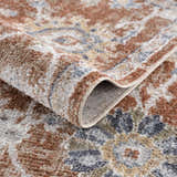 Close-up of the Chavi Washable Area Rug, showcasing its traditional floral pattern and soft charcoal, clay, and brown colors. Fold