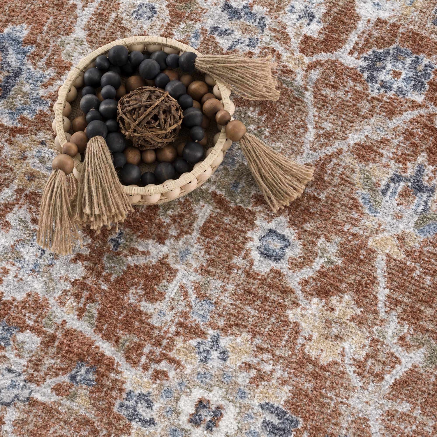 Close-up of the Chavi Washable Area Rug in charcoal, clay, and brown. Farmhouse style rug with a traditional floral pattern. Styleshot