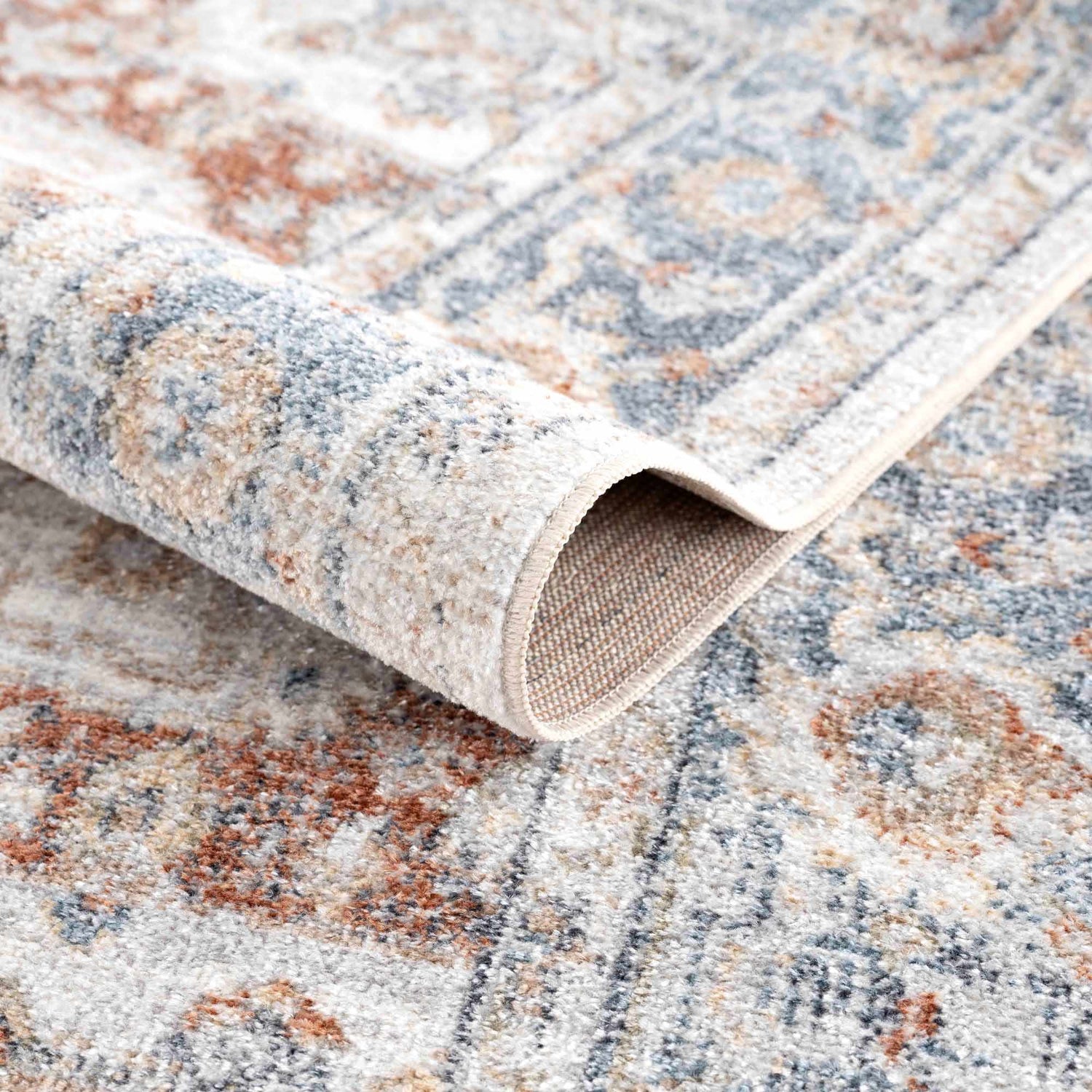 Close-up of the Neta Red & Blue Flat Pile Washable Rug showing the oriental design, soft texture, and durable backing. Fold